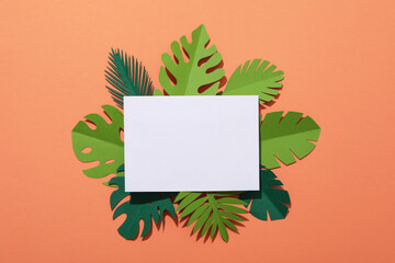 Paper green tropical leaves on a peach background.