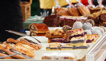 Bakery stand with variations of pastries, brownies, pies, cakes, and other desserts at strret food market in Prague.