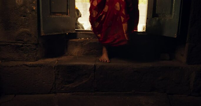 Slow Motion Close Up On The Feet of an Indian Woman Stepping into an Ancient Temple. Devoted Female in a Beautiful Red Sari Walking Inside her Place of Worship, Seeking Guidance and Wisdom