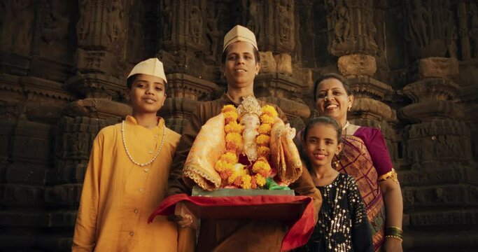 Portrait of Happy Indian Family Looking at the Camera, Holding a Statue of their Deity. Authentic Footage of Traditional Family Posing with a Representation of the God of Good Luck in Hinduism, Ganesh