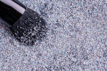 Grey and silver powder eye shadow with glitter and brush. Top view of silver glitter and make-up brush, macro. Makeup concept