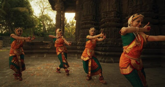 Portrait of Expressive Young Females Dancing Folk Dance Choreography in Temple. Indian Women in Colourful Traditional Clothes Beautifully and Swiftly Performing Bharatanatyam Dance Moves 