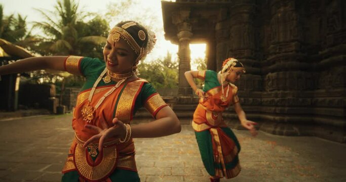 Slow Motion Portrait of Indian Women in Traditional Clothes Dancing Bharatanatyam in Colourful Sari . Close-up on Expressive Young Females Performing Folk Dance Choreography in an Ancient Temple