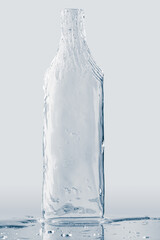 Textured bottle form, made from clean, transparent ice, isolated on light grey background. Purity and freshness concept.
