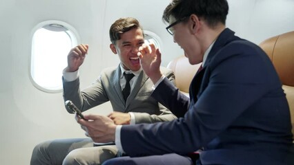 Excited young partner asian businessman sit and working on laptop in seat on the plane hand up to celebration for success of work, online business. Congratulation good news while flying airplane. - Powered by Adobe