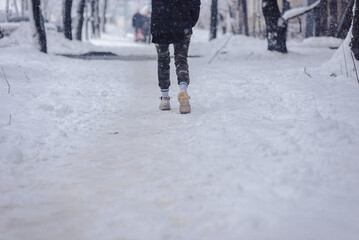 legs of a person walking along a snowy city street in summer shoes