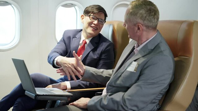 Young businessman and senior using laptop sitting near window on first class in plane during flight. Passenger business partner,  Wealthy company executive travel working. Traveling and Business.