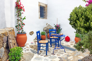 Fototapeta na wymiar typical greek style terrace with table chairs and plants