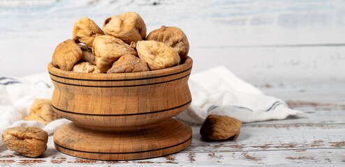 Dried figs in wooden bowl. Sun-dried natural figs on a white wood background. Copy space. Empty space for text