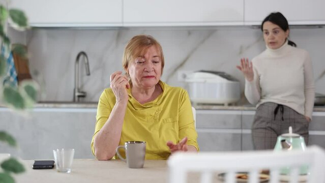 Portrait of a frustrated mature woman in an apron, offended by her daughter after a quarrel in the kitchen at home. . High quality 4k footage