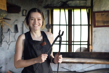 Young woman blacksmith portrait in workshop