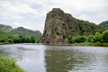 Fototapeta na wymiar Lake and huge rock. Beautiful nature, the river flows downhill. Green forests and mountains