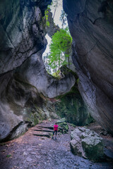 Frau in einer Höhle, die oben offen ist und durch den Spalt Licht hereinlässt, mit Pflanzen...