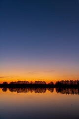 Naklejka premium beautiful orange-yellow sunset on the lake in spring