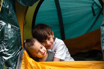 Little boy and little girl hugging while sitting in a tent