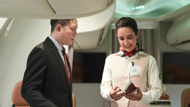 Beautiful and attractive asian flight attendant staff smiling. Passenger giving passport with boarding pass to air hostess woman check on airplane. Cabin crew or stewardess occupation concept.