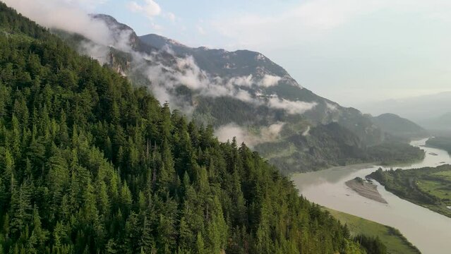 Aerial ascent over forest to Squamish River and clouds, Squamish, BC, Canada