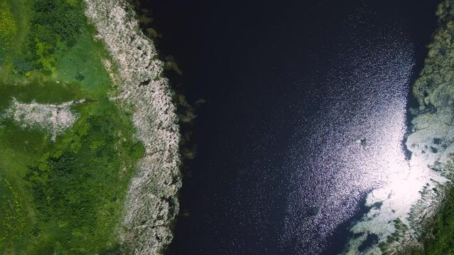 Drone Flies Down Shore of a Shimmering Summertime Grassy Riparian Blue Water Cattail Island Wetland on Outdoor Lake Habitat Farmland Park in Brandon Manitoba Canada