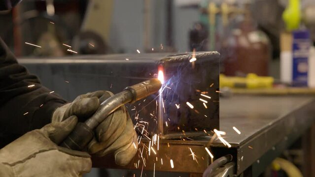 Man mig welding metal bracket in machine shop