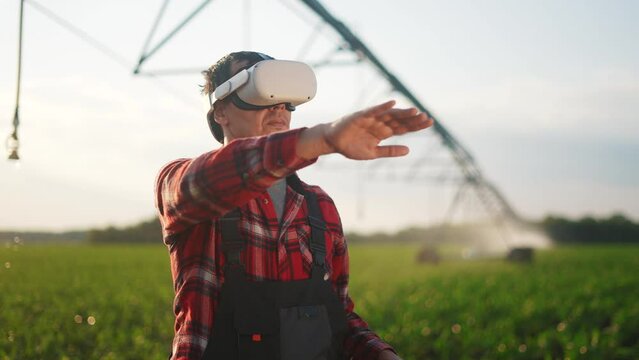 agriculture virtual reality. a farmer in virtual reality glasses controls a machine to irrigate corn field. agriculture virtual reality concept. business a farmer vr in works in field with corn