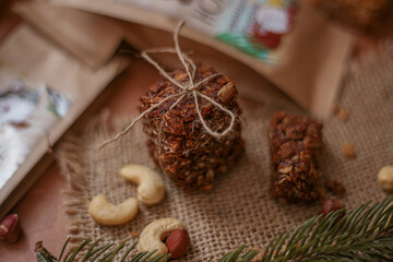 a healthy granola bar for a snack lies on a wooden table along with nuts