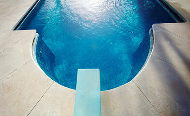 Diving board view from above and blue water of swimming pool