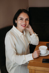 Beautiful woman holding coffee cup while sitting at cafeteria