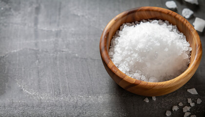 Fototapeta na wymiar Coarse salt in a wooden bowl on a gray kitchen table.