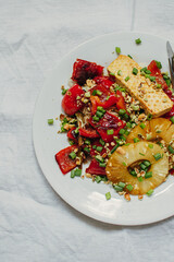 Healthy vegetarian lunch from tofu cheese, vegetables and nuts on light background. Top view. Free space for your text.