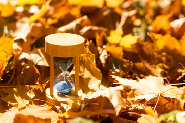 Autumn time theme, Sandglass on fallen leaves in various colors with copy space