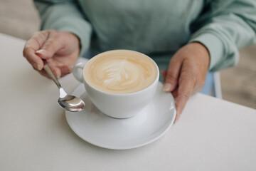 Closeup image of a man and a woman clinking white coffee mugs in cafe. High quality photo