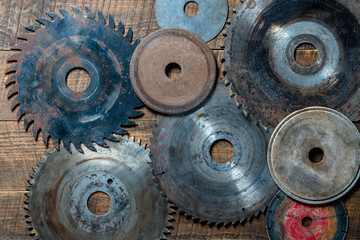 Old circular saw blades and emery wheels on wooden table, closeup, top view. Carpentry tools, sawing and grinding equipment - obrazy, fototapety, plakaty