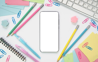 Smartphone with white screen and school supplies around on the table. Online learning concept. Mockup. Flatlay. Top view. Copy space.