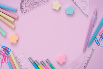 School stationery lie in the shape of a frame on pink background. Back to school. Flatlay composition. Top view. Copy space.