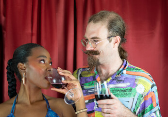 African Woman looking white man with glasses and big mustache drinking wine
