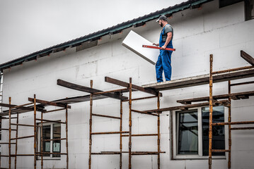 Master with adhesive Styrofoam to the wall by facade. Building insulation saves energy.