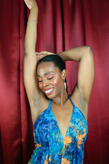 Fototapeta na wymiar African Woman ethnicity with blue dress dancing and smiling in red background