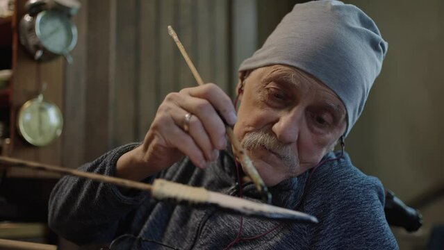 Elderly male master works in his workshop restoring japanese deba knife sheath