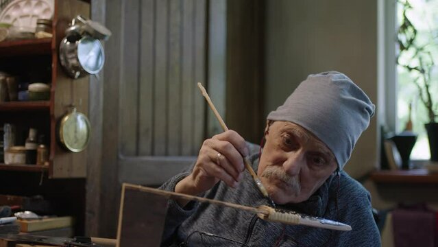 Elderly male master works in his workshop restoring japanese deba knife sheath