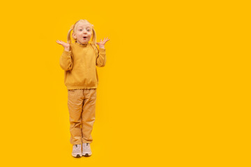Girl is screams or surprised. Space for text, mock up. Full-length portrait of little girl in yellow suit on yellow background