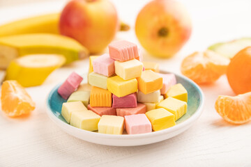 Various fruit jelly chewing candies on white wooden. apple, banana, tangerine, side view, selective focus.