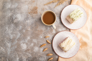 Roll biscuit cake with cream cheese and jam, cup of coffee on brown concrete, top view, copy space.
