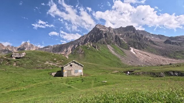 Time lapse of an alpine landscape. Clouds moving over high summits and little mountain huts in Switzerland