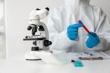 A doctor's hand holds a small vial with a blood test next to other samples. check your blood Close-up shot of a male scientist in a white uniform while working in a laboratory.