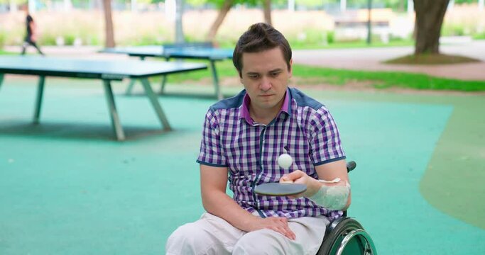 A man in a wheelchair rides in the park. A disabled person plays tennis. Disabled person on the sports ground on a sunny day.
