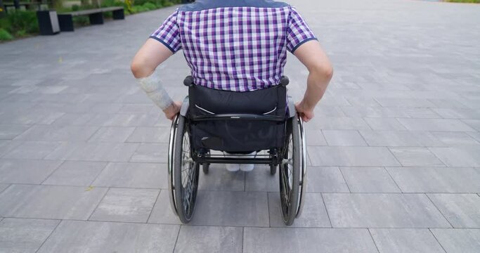 A man in a wheelchair rides in the park. A disabled person plays tennis. Disabled person on the sports ground on a sunny day.