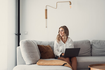 Portrait of one young attractive blonde woman using laptop pc computer on couch relaxing surfing...