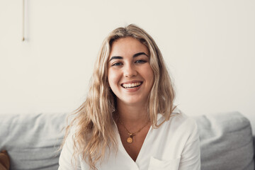 Close up overjoyed woman laughing, sitting on couch at home, head shot portrait young female...