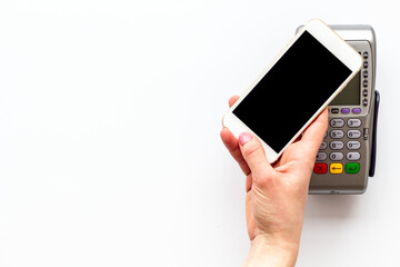 Payment by mobile phone pay. Female hand with mobile phone near POS payment terminal