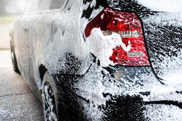 New black modern car sprayed with washing foam. Washing the car.